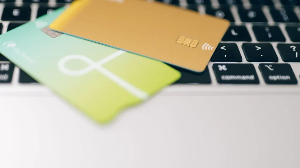 Two credit cards resting on a laptop keyboard.
