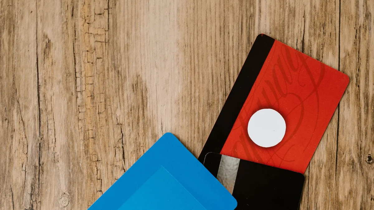 Red, blue and black credit cards arranged on a wooden surface.
