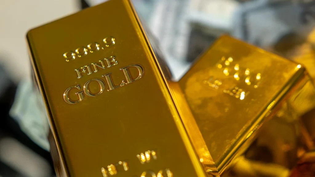 Close-up of gold bars with banknotes blurred in the background.