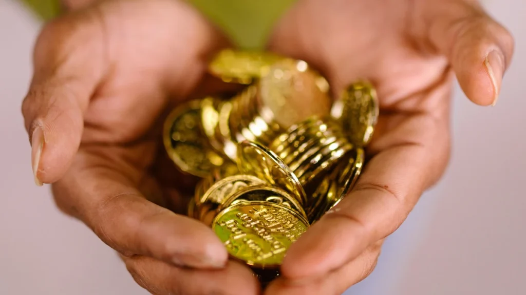 Close-up of hands holding a pile of shiny gold coins.