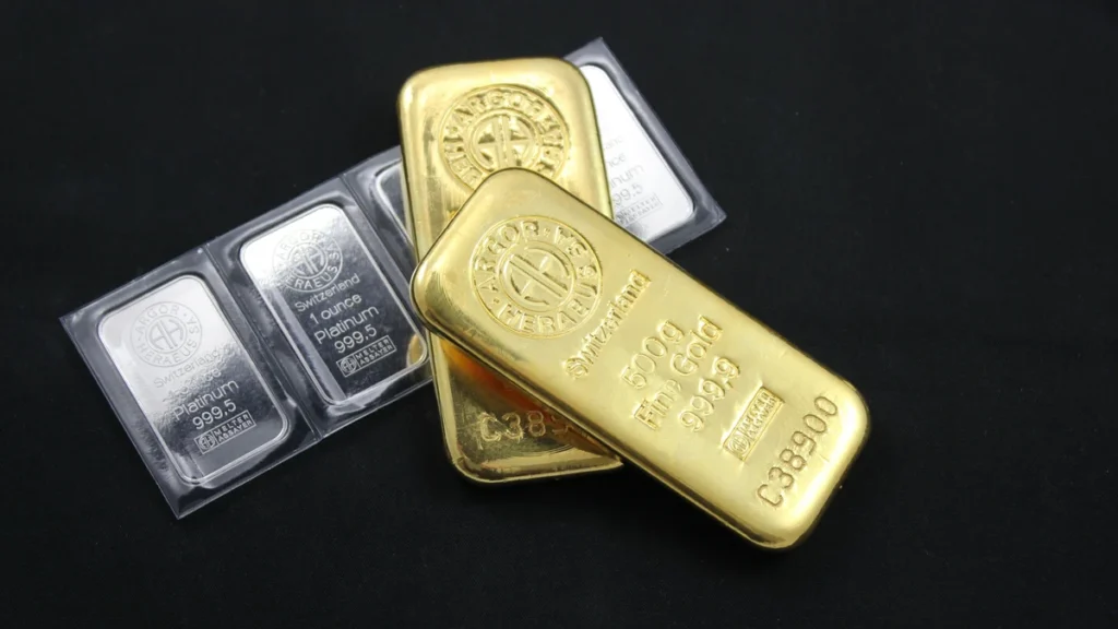 Gold and platinum bullion bars arranged on a dark surface.