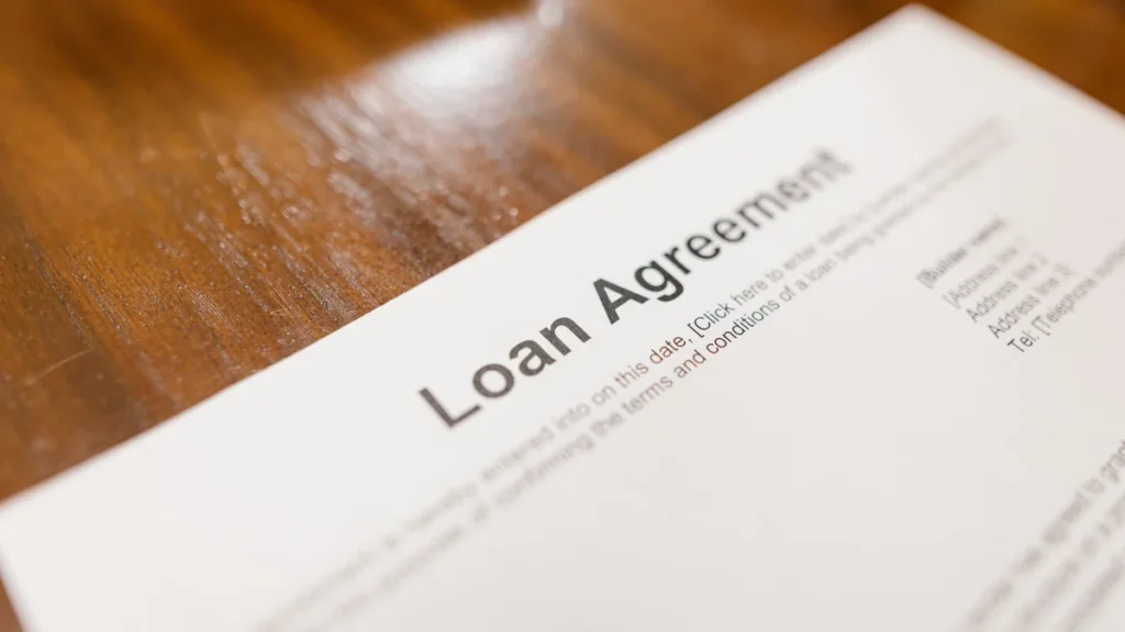 Close-up of a loan agreement document on a wooden table.