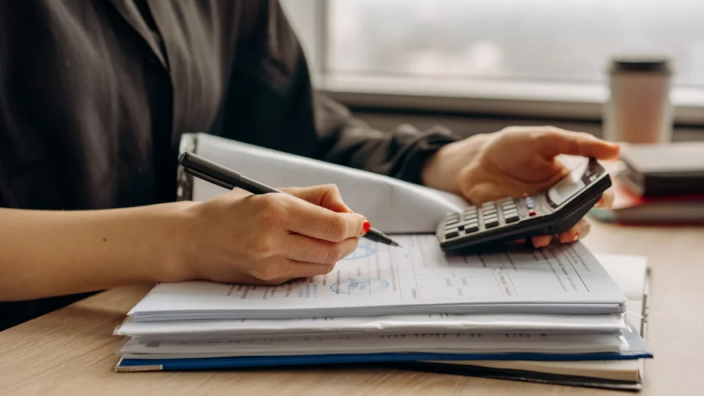 Person using a calculator while reviewing financial documents at a desk.
