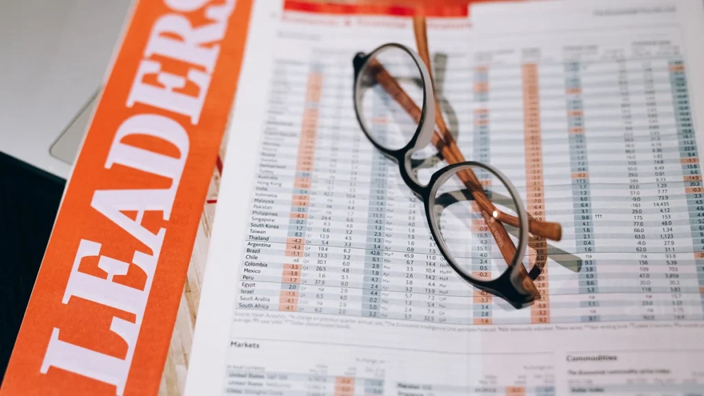 Eyeglasses resting on printed financial market tables and reports.