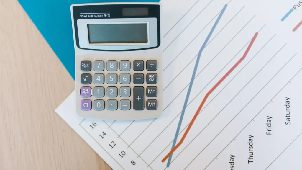 Calculator resting on a printed line chart on a desk.