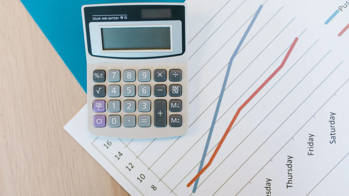 Calculator resting on a printed line chart on a desk.