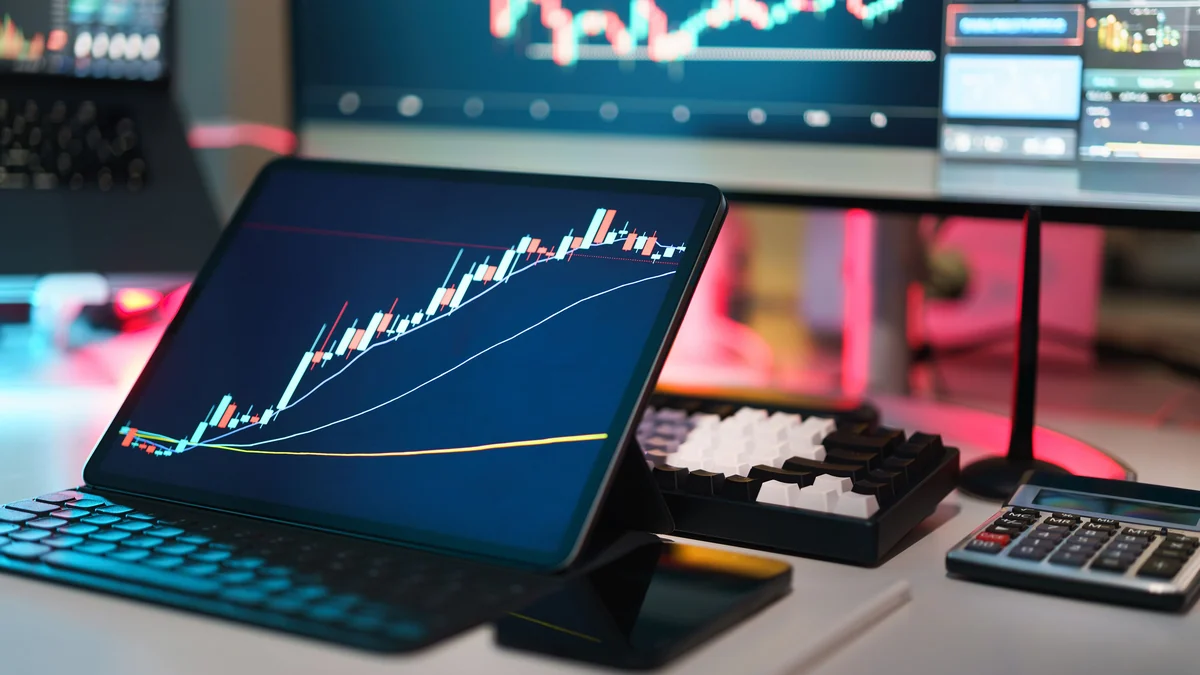 Trading screens displaying financial price charts on a desk.
