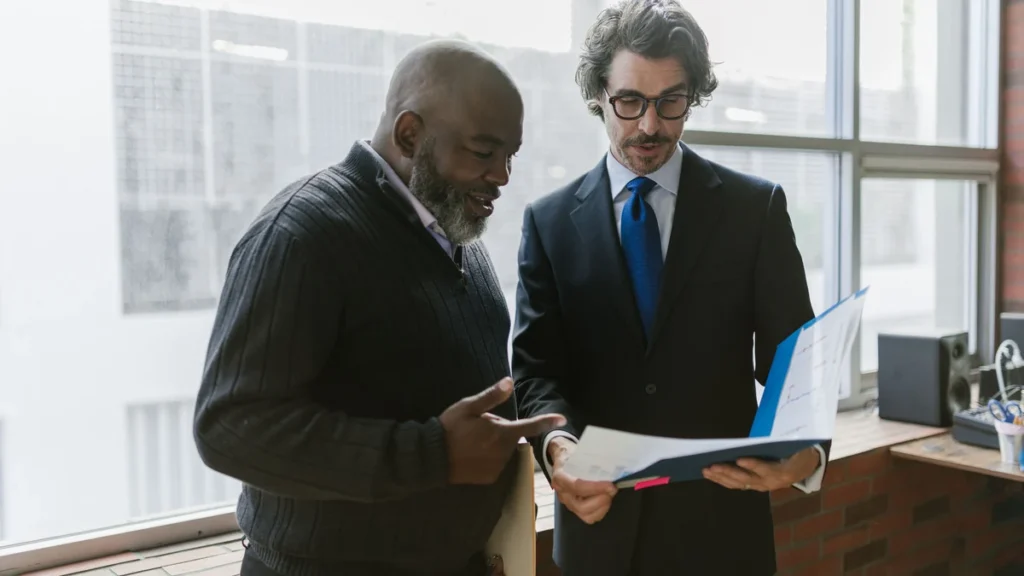 Two business professionals reviewing charts and documents together in an office.