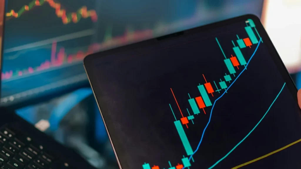 Trading charts displayed on a tablet and multiple computer screens.