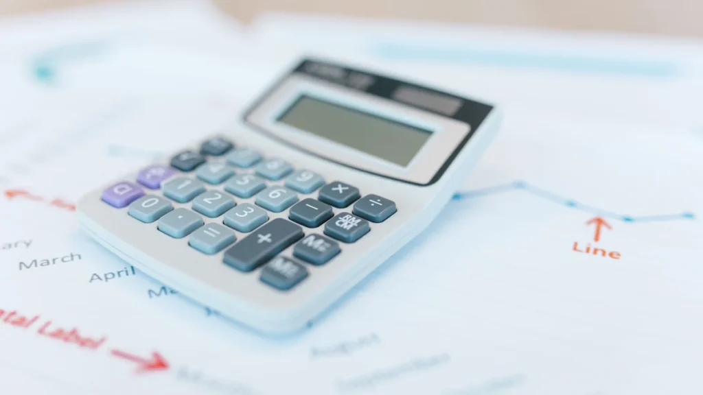 Calculator resting on financial charts and analysis documents.