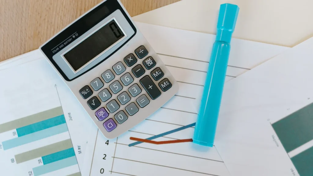 Calculator and financial charts on a desk used for investment analysis.