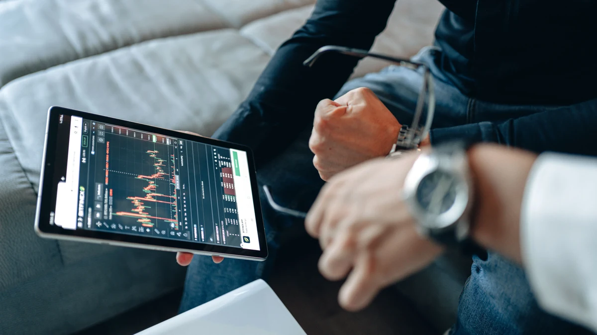 Two people reviewing financial market charts on a tablet.