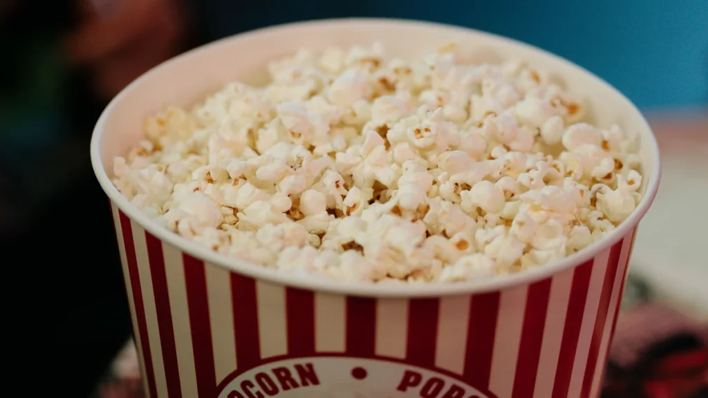 A red-and-white bucket filled with popcorn in an entertainment setting.
