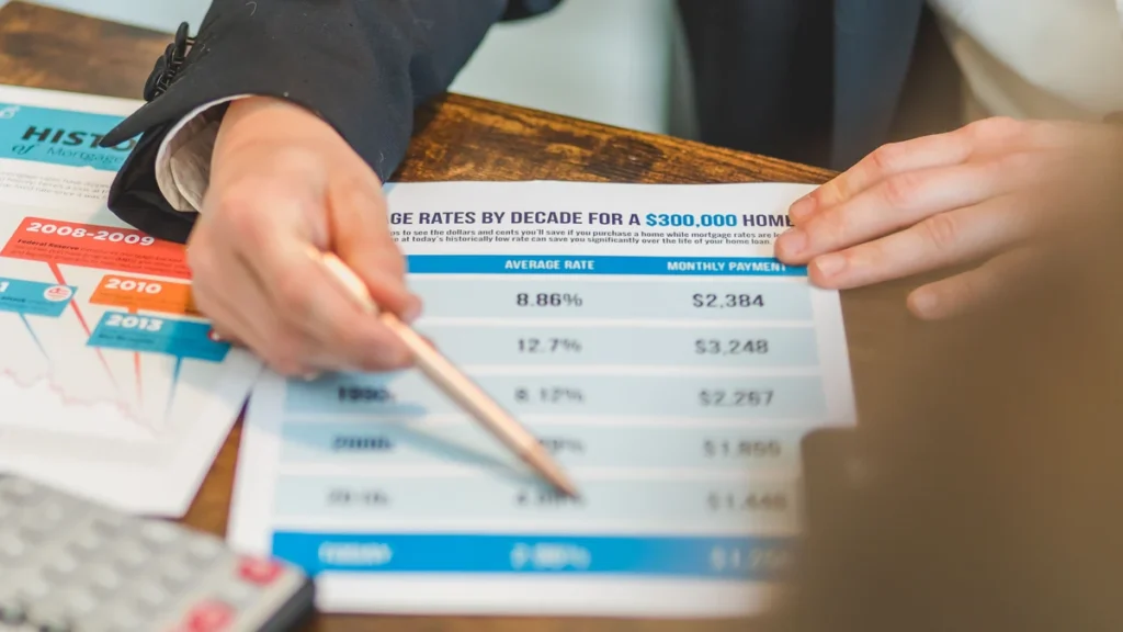 Hands reviewing a mortgage rate chart on a desk with a calculator nearby.