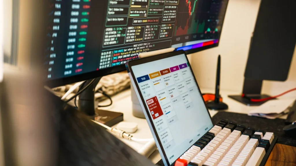 Trading desk with multiple monitors displaying financial charts and market data.