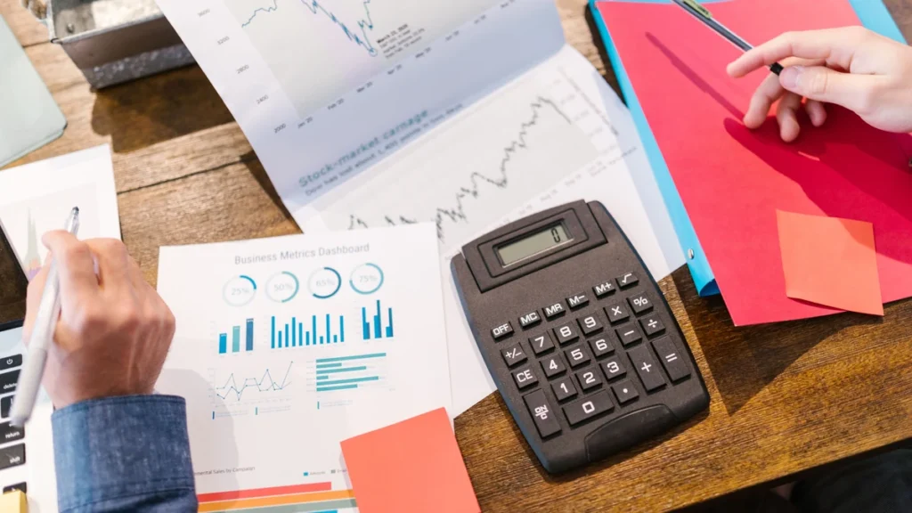 Financial charts, reports and a calculator arranged on a desk.