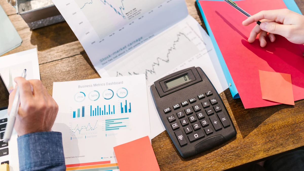 Financial charts, reports and a calculator arranged on a desk.