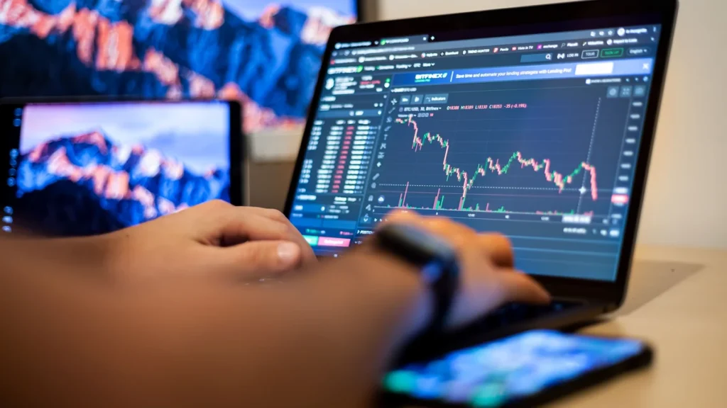 Hands using a laptop displaying a financial trading chart.