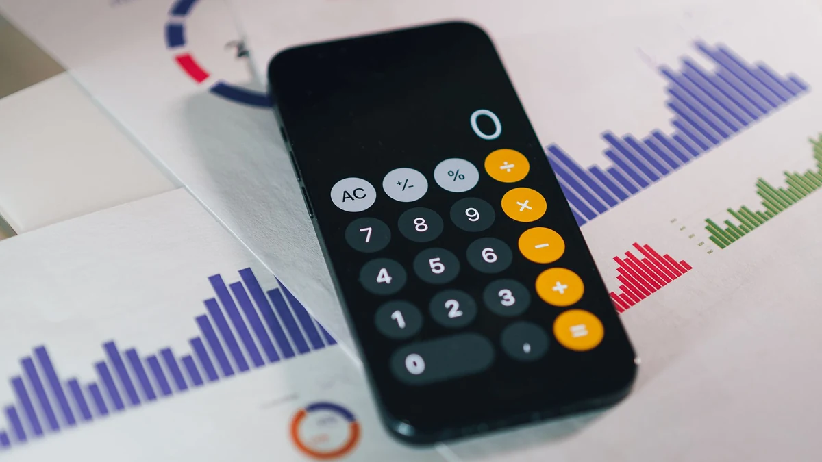 Calculator resting on printed financial charts and reports.