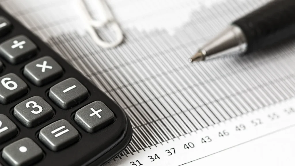 Calculator and pen resting on a printed financial chart.