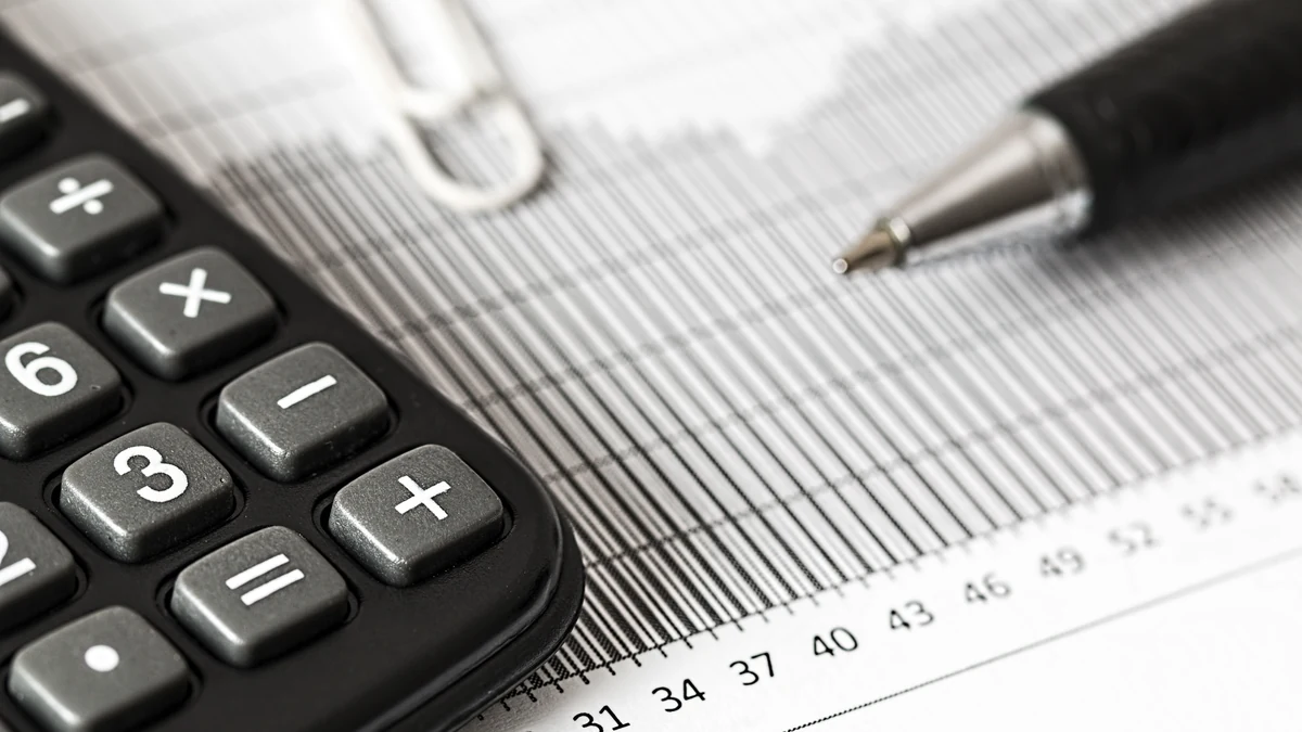 Calculator and pen resting on a printed financial chart.