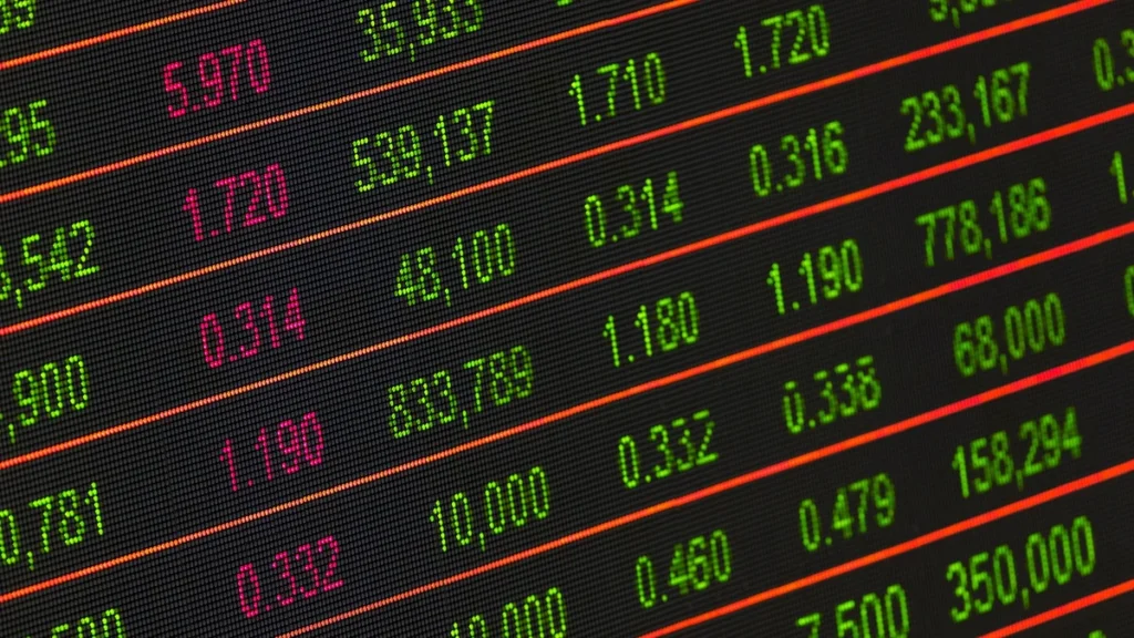 Close-up of an electronic stock market display showing rows of green and red market figures.