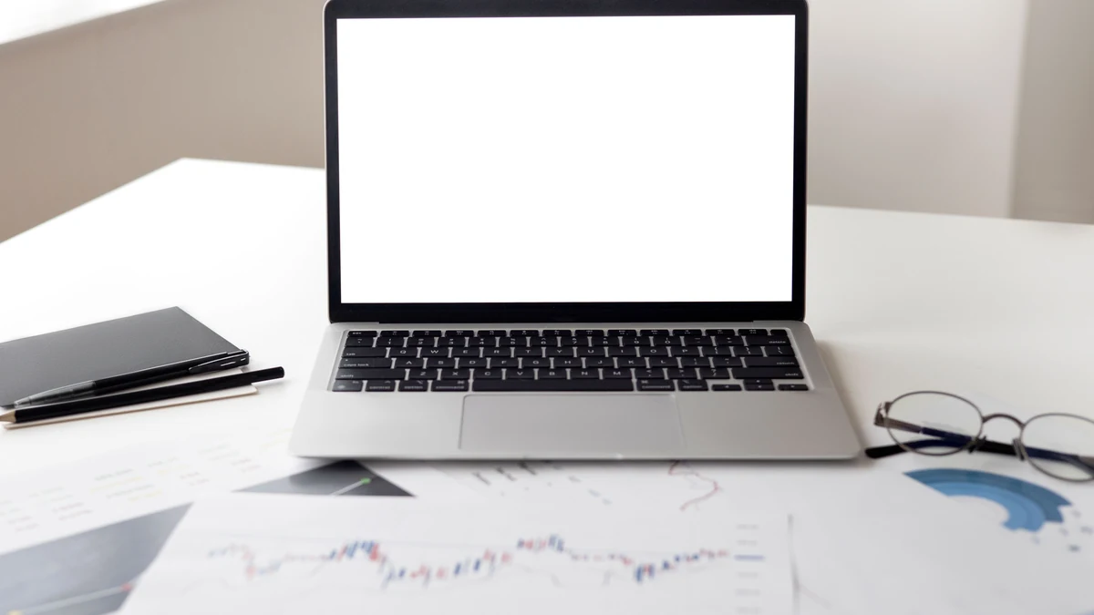 Laptop and printed financial charts on a desk.