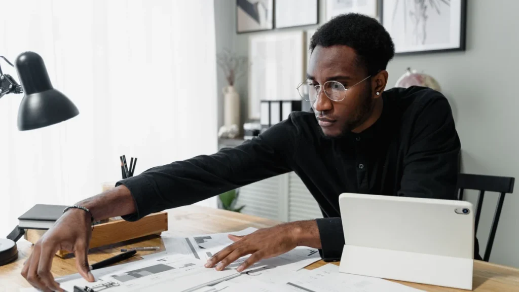 Business professional reviewing financial documents at a desk with a tablet.