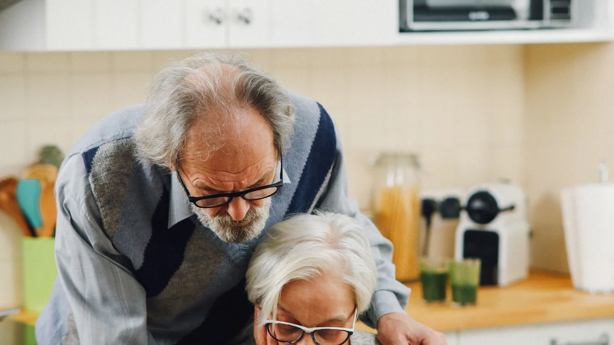 An older couple reviewing financial documents together at a kitchen table.