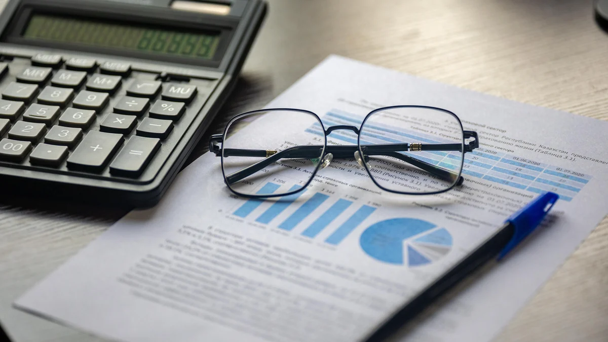 A calculator, eyeglasses and pen resting on a financial report.