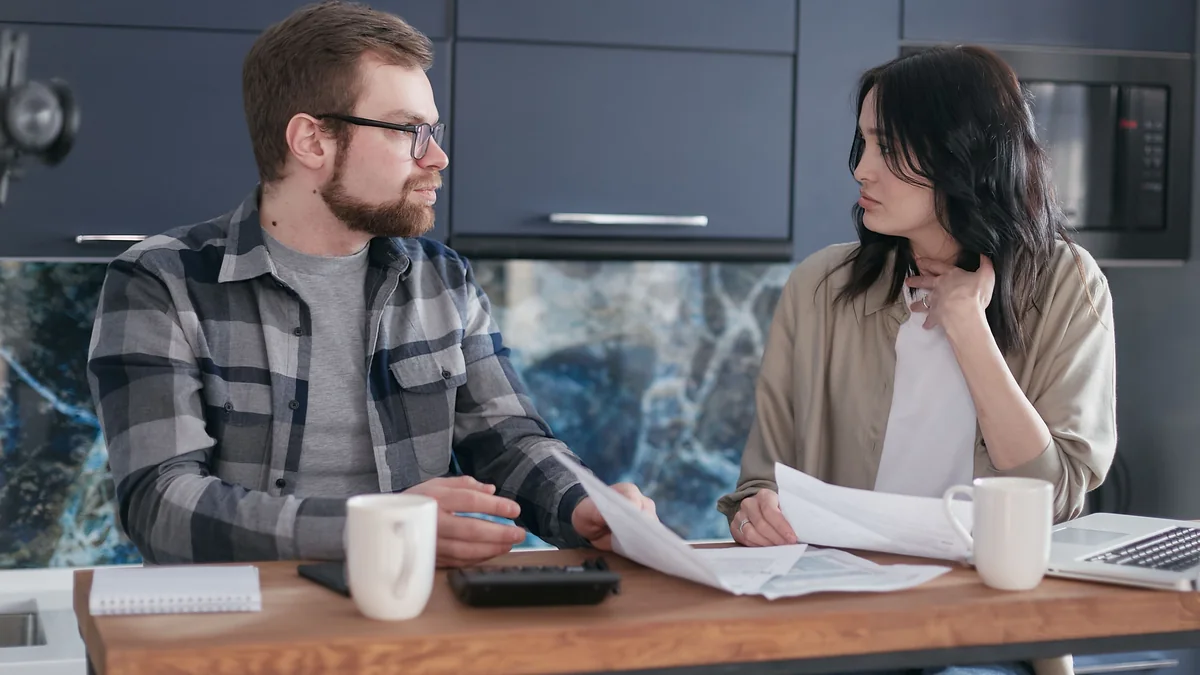 Couple reviewing financial documents together at a kitchen table.