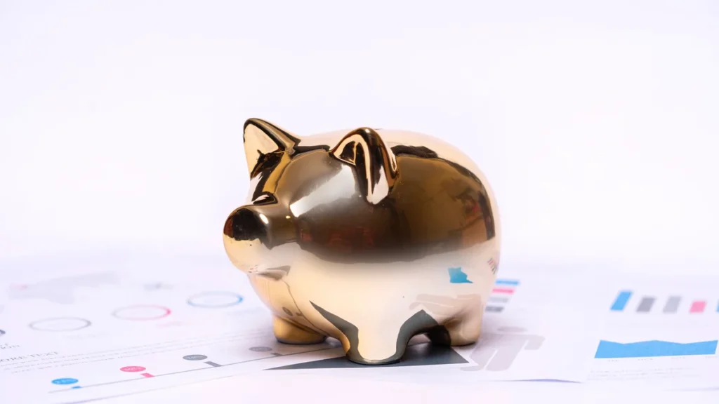 A gold piggy bank resting on financial charts and documents.
