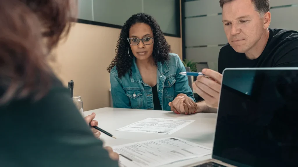 A couple reviewing financial documents with a professional at an office table.