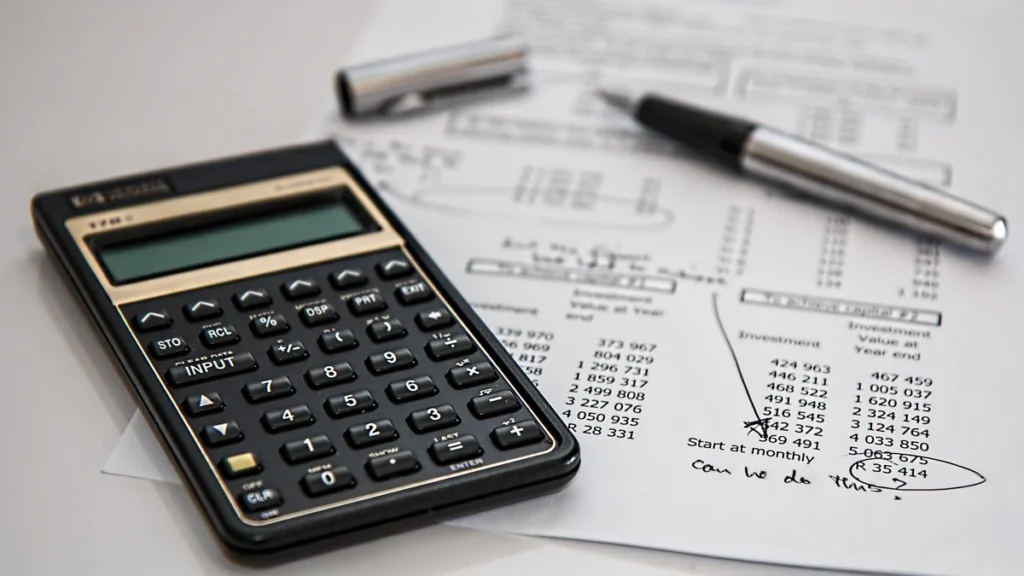 A financial calculator beside investment-planning documents and a pen.