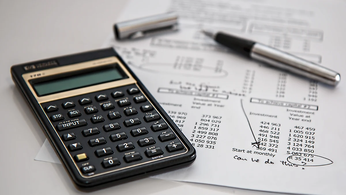 A financial calculator beside investment-planning documents and a pen.