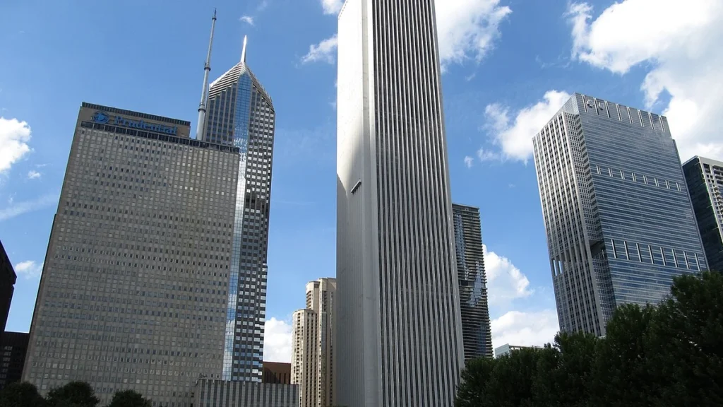 Chicago skyline with the Aon Center tower standing prominently in the middle under a blue sky.