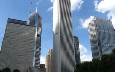 Chicago skyline with the Aon Center tower standing prominently in the middle under a blue sky.