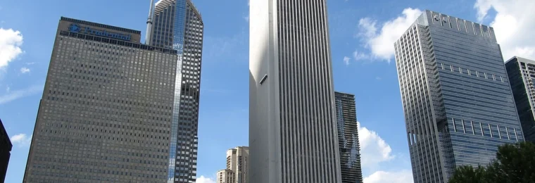 Chicago skyline with the Aon Center tower standing prominently in the middle under a blue sky.