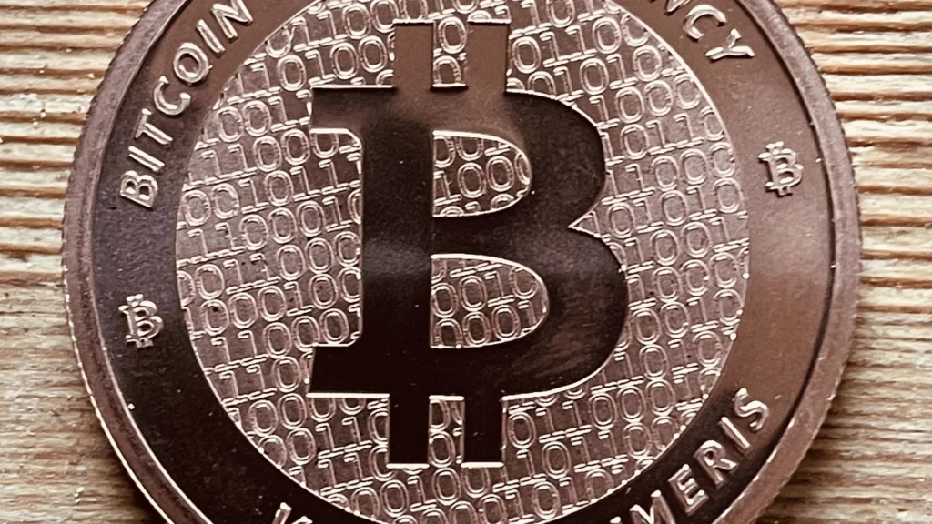 Close-up of a physical Bitcoin-themed coin on a wooden surface.