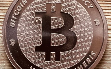 Close-up of a physical Bitcoin-themed coin on a wooden surface.