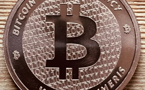 Close-up of a physical Bitcoin-themed coin on a wooden surface.