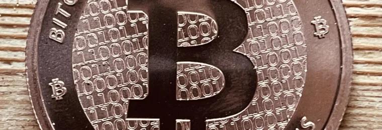 Close-up of a physical Bitcoin-themed coin on a wooden surface.