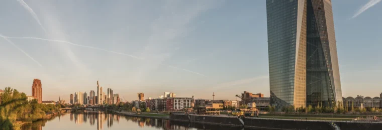 European Central Bank headquarters beside the Frankfurt skyline at dawn.