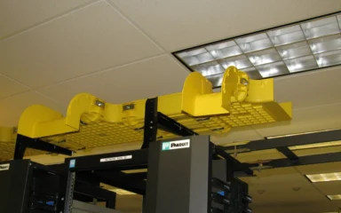 Yellow fiber-optic cable management trays above networking racks.
