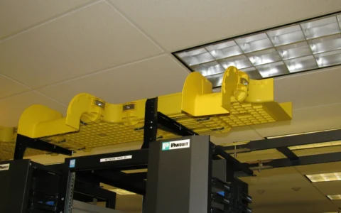 Yellow fiber-optic cable management trays above networking racks.