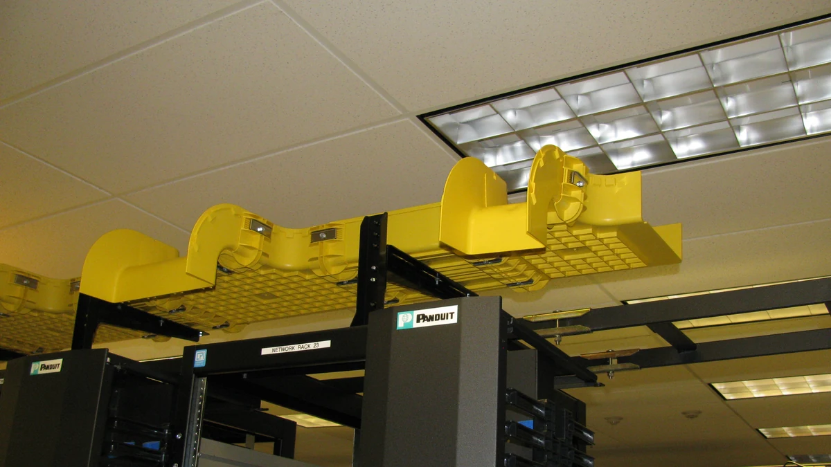 Yellow fiber-optic cable management trays above networking racks.