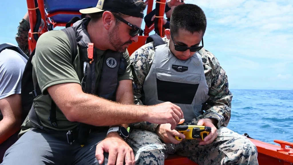 U.S. Marine Corps staff sergeant holding a FORT Robotics remote controller beside a Department of Navy civilian in Okinawa.