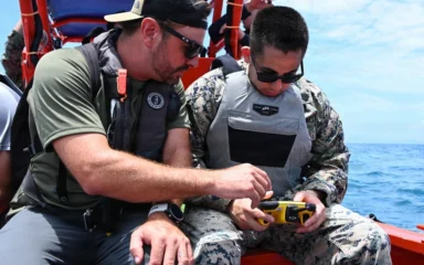 U.S. Marine Corps staff sergeant holding a FORT Robotics remote controller beside a Department of Navy civilian in Okinawa.