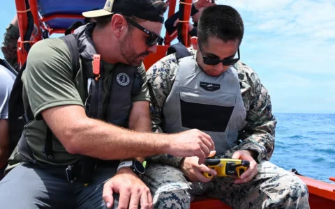 U.S. Marine Corps staff sergeant holding a FORT Robotics remote controller beside a Department of Navy civilian in Okinawa.