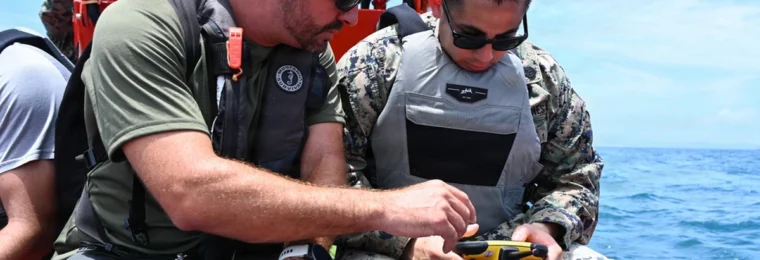 U.S. Marine Corps staff sergeant holding a FORT Robotics remote controller beside a Department of Navy civilian in Okinawa.